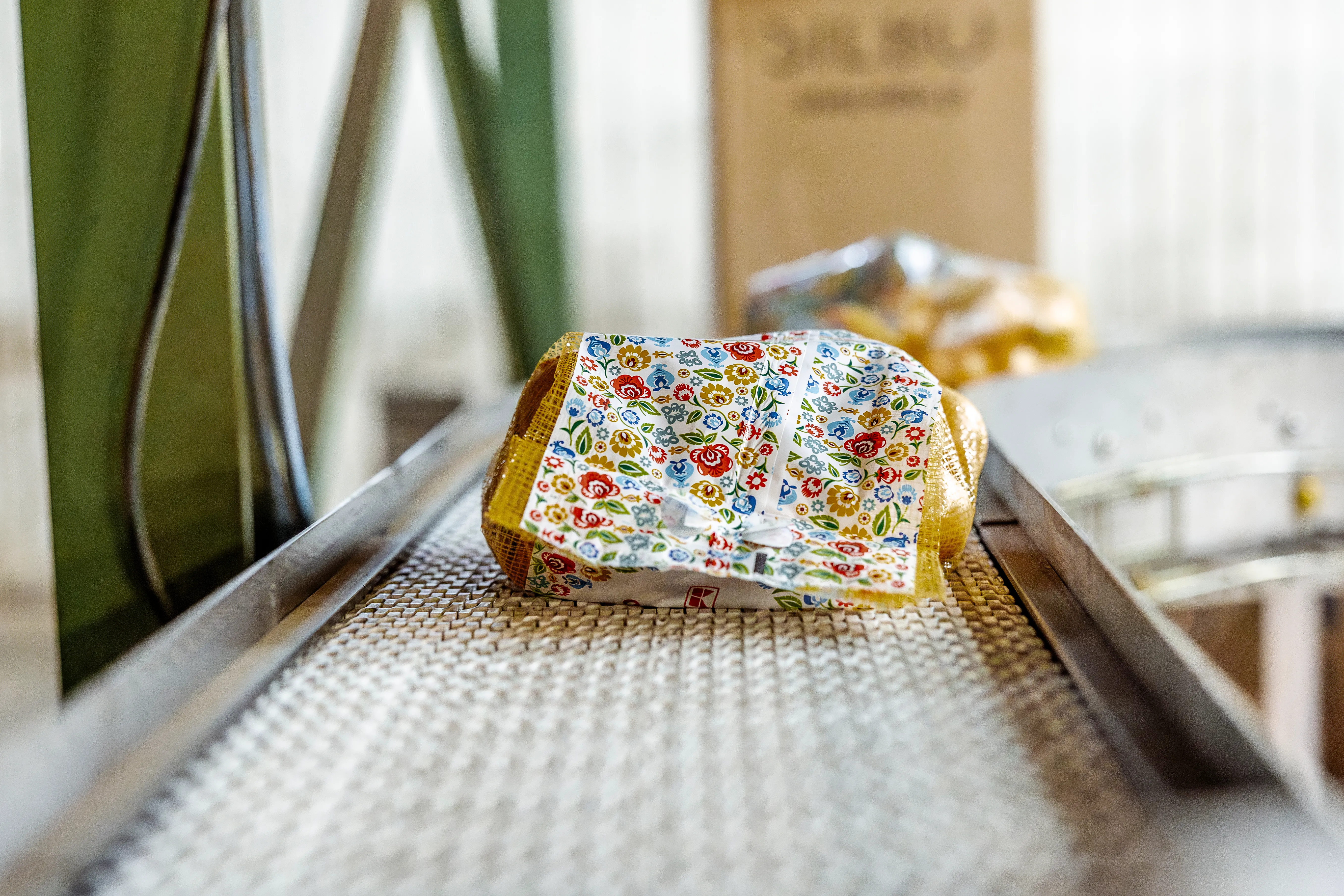 Linia produkcyjna w zakładzie Agrosad, na niej ziemniaki w worku z kolorową etykietą